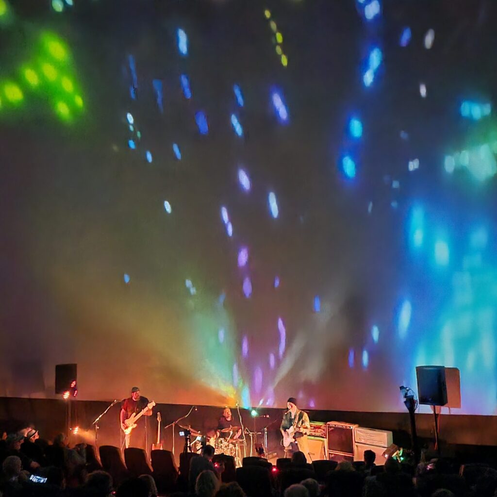 Concert footage with graphics on a screen behind the band