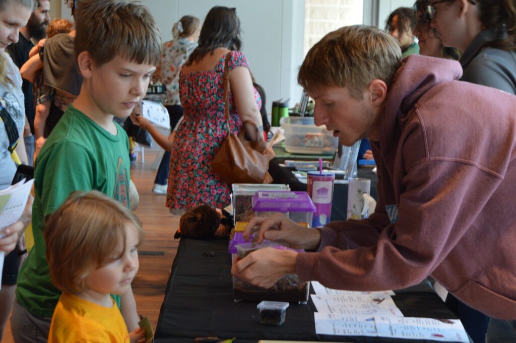 Exhibitor shows a bug to watching children