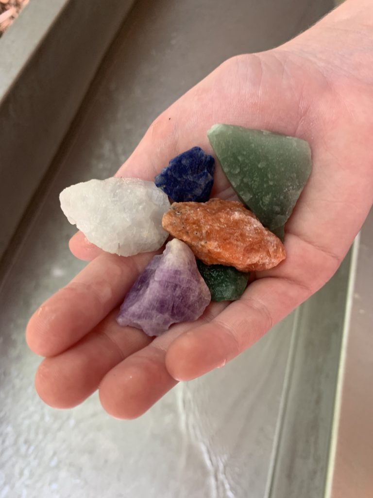 Pciture of differest gemstones in a person's hand found during gemstone mining