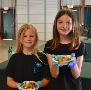 Two girls show off food from Farmer's Market