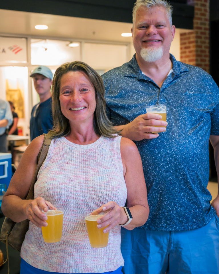 A couple holds glasses of beer in the lobby of The Schiele Museum