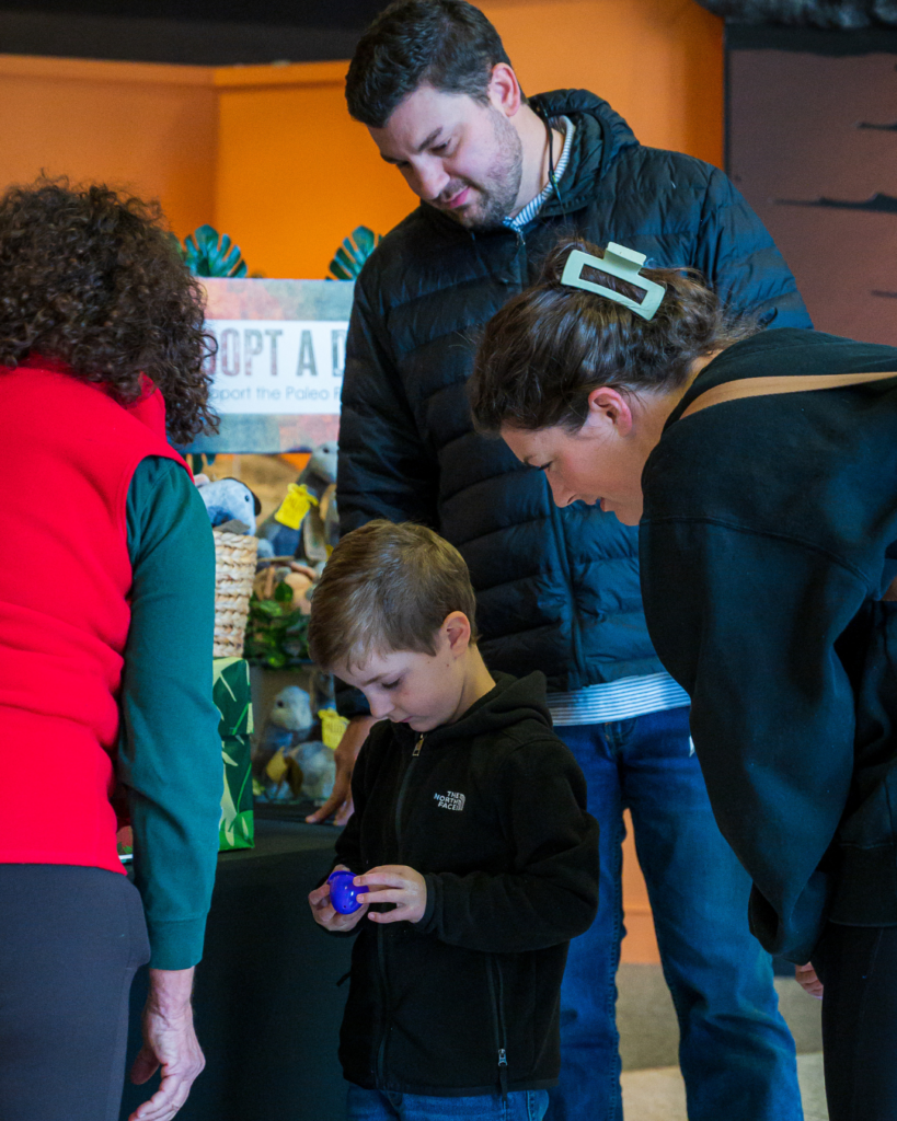 A family watches a young boy open a plastic egg