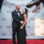 A couple embracing in front of a dino backdrop