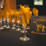 wine glasses and Schiele dinosaur card on black background
