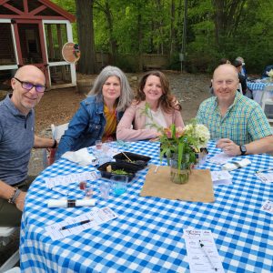 2 men and 2 women sitting at a table posing for picture for Wine Beer Tasting